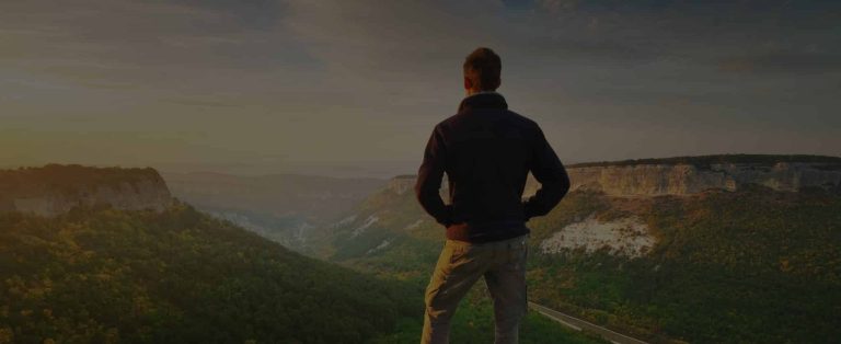 a man standing on a cliff overlooking a valley