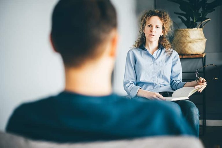 a woman sitting in front of a man at therapy session