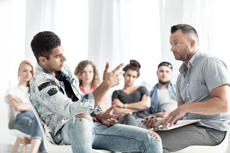 a man sitting in a chair talking to a man at aa meeting